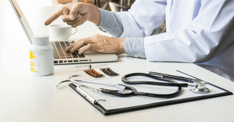 A healthcare professional analyzing financial data on a laptop with medical tools on the desk, symbolizing hospital costing and pricing evaluation.