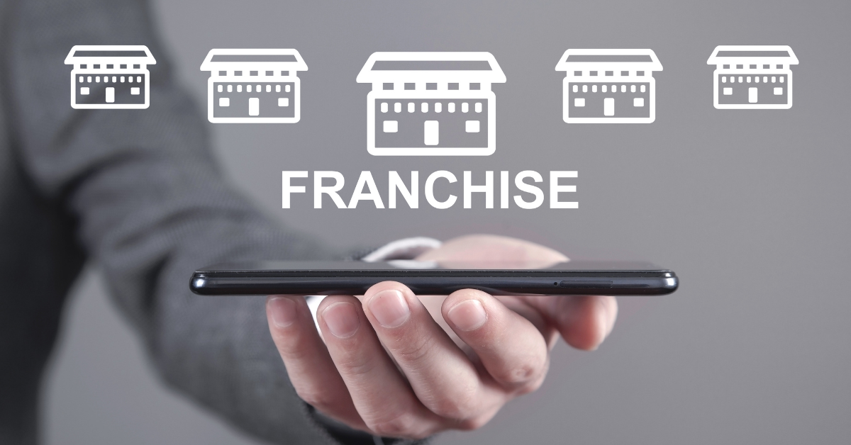 A business professional holding a smartphone with multiple franchise icons above it, representing digital connectivity and financial systems integration for franchise networks.