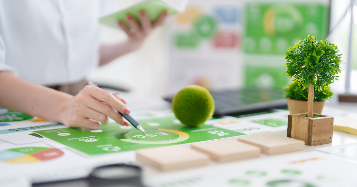 A professional reviewing ESG performance data with sustainability icons and small plants on a desk, symbolizing financial stewardship and environmental responsibility.